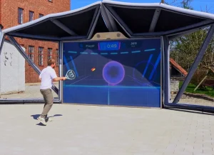 Entrenamiento o juego de tenis individual en simulador con tecnología interactiva y marco exterior.
