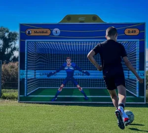 Simulador de fútbol MultiBall en evento interactivo con niño pateando a portero digital.