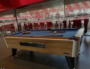 mesa de billar largas con paño beige/verde claro en un salón amplio.