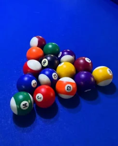 Primer plano de un conjunto de bolas de billar de colores vibrantes sobre un paño azul eléctrico.