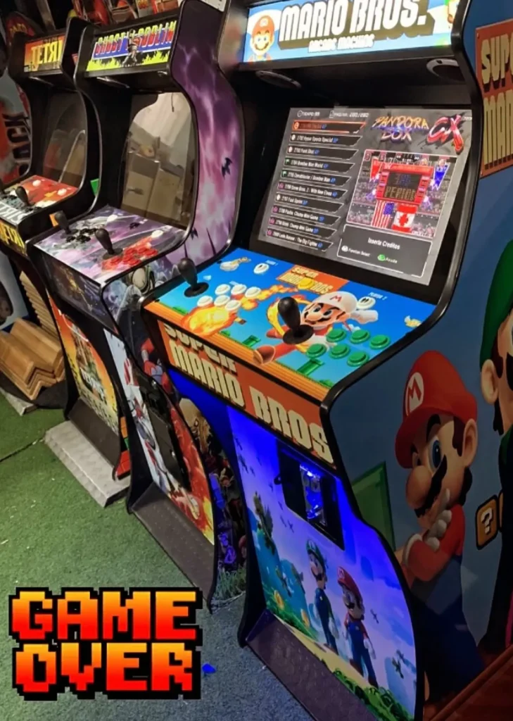 Fila de máquinas arcade retro con vinilos de personajes clásicos de videojuegos como Mario Bros, mostrando pantallas de selección de juegos en un salón recreativo.
