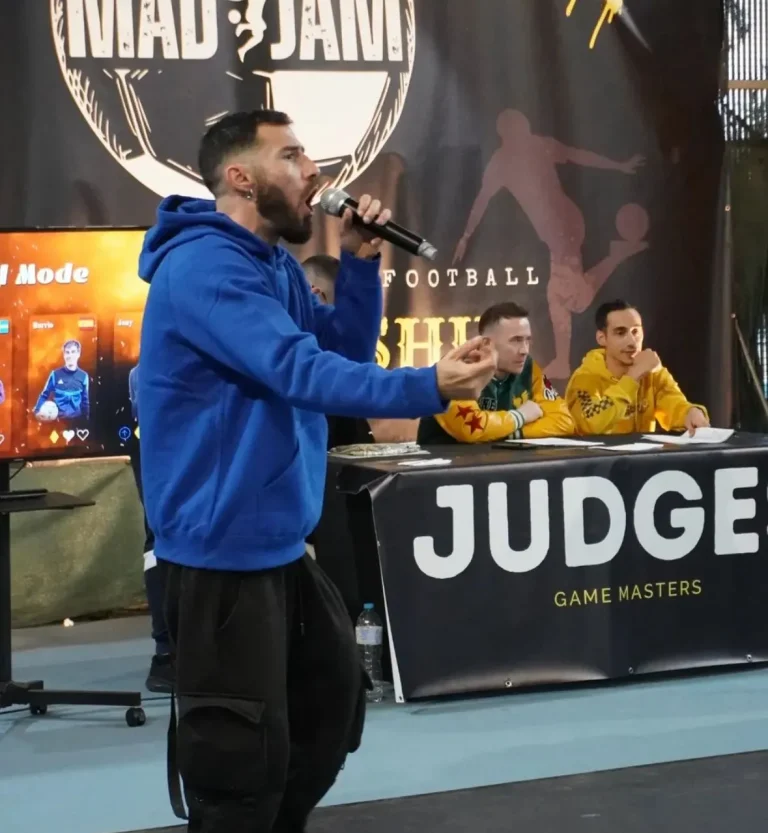 Speaker profesional animando una competición de fútbol freestyle en un evento indoor.