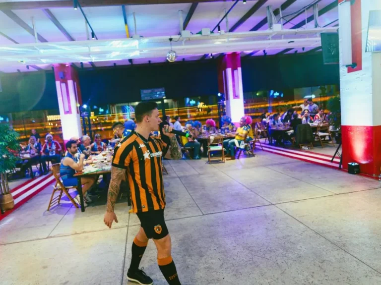 Speaker caminando en evento corporativo interior con micrófono, interactuando con los invitados.