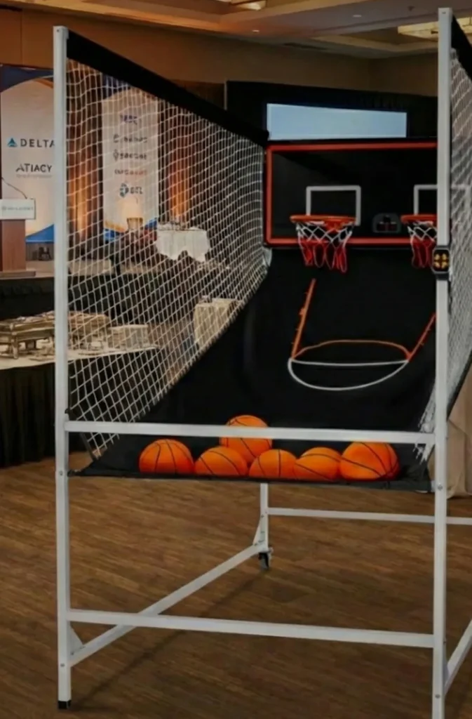 Máquina de baloncesto arcade profesional de estructura blanca instalada en el interior de un salón para eventos corporativos.