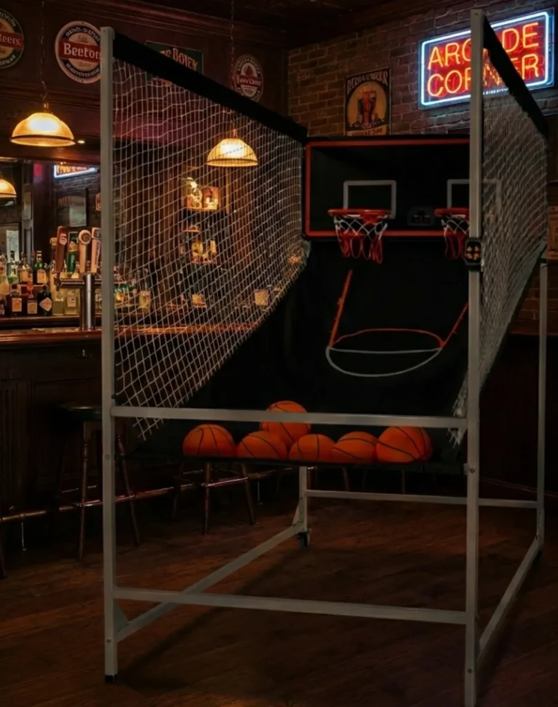Estación de baloncesto "Arcade Corner" con iluminación cálida, ideal para zonas de ocio y eventos nocturnos en interiores.